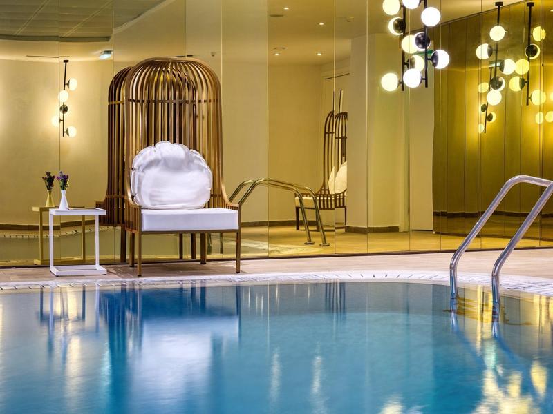 Moderner Innenpool mit blauem Wasser, weißen Stühlen und warmen, gelben Wänden.