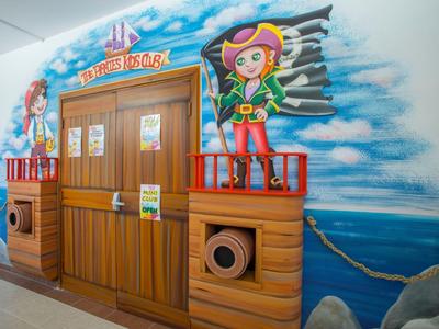 Bunte Piratenschiff-Wandmalerei mit Holzdetail und Segel vor einem Hotelzimmer-Eingang.