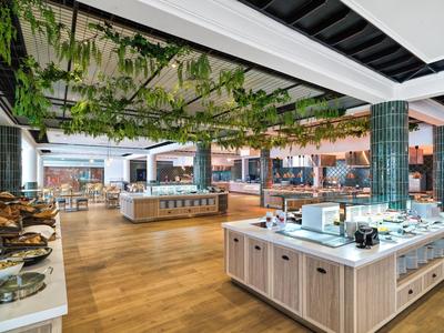 Modernes Buffetrestaurant mit Holzboden, hängenden Pflanzen und vielfältigen Essensstationen.