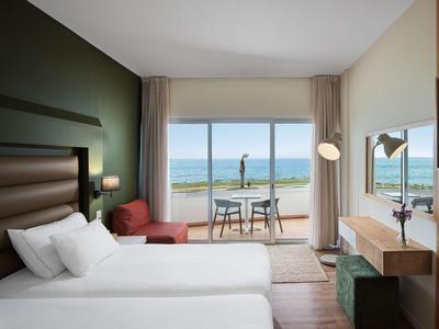 Modernes Hotelzimmer mit zwei Betten, Balkon und Meerblick.