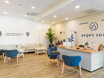 Modernes Spa-Wartezimmer mit blauen Sesseln, Holzboden und weißer Rezeption.
