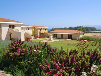 Vue d'une maison de vacances avec jardin et arbustes en fleurs sous un ciel bleu clair.