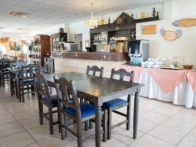 Interno di un ristorante luminoso con sedie di legno e tavoli apparecchiati.