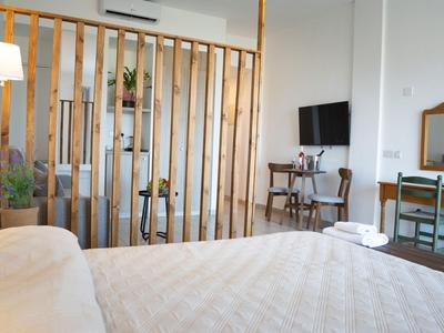 Camera d'hotel luminosa con letto, scrivania, TV e separé in legno in stile moderno.