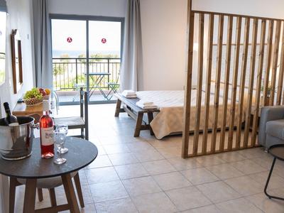 Camera d'hotel moderna con tavolo per la colazione, divano e divisorio.