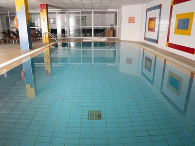 Piscina interna con piastrelle blu pulite e decorazioni murali moderne in un hotel.