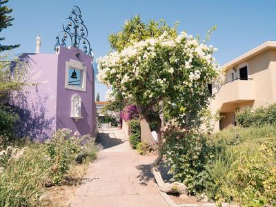 Un sentiero tra una torre viola e un edificio beige con un albero in fiore dietro.