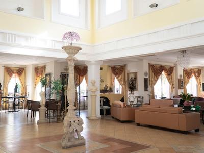 Luminoso atrio d'hotel con comodi divani, colonne e grandi finestre che creano un'atmosfera accogliente.
