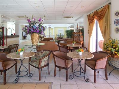 Ein heller Gastraum mit runden Tischen, braunen Stühlen und großen Blumenarrangements.