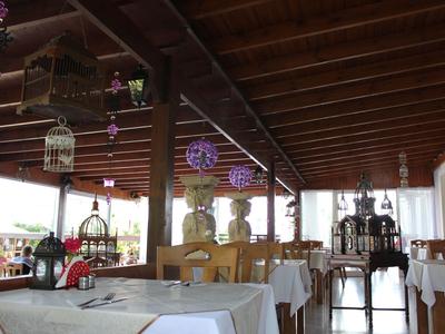 Espace extérieur couvert d'un restaurant avec nappes blanches et éclairage décoratif.