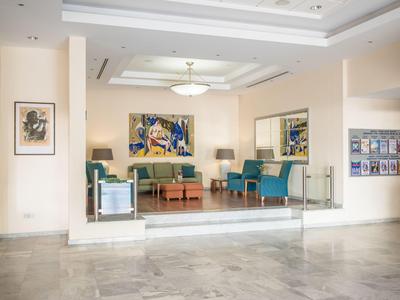 Lichte hotel lobby met zithoek, banken, fauteuils en kunst aan de muren.