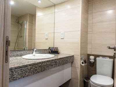 Helles Badezimmer mit grauer Granit-Arbeitsplatte, rundem Waschbecken, Spiegel und Toilettenanlage.