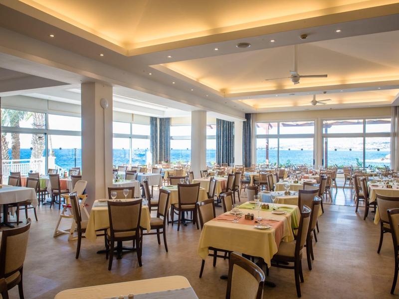 Helles, modernes Restaurant mit Holzstühlen, gedeckten Tischen und großen Panoramafenstern mit Aussicht.