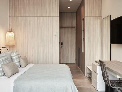 Modernes Schlafzimmer mit hellen Holzmöbeln, großem Bett, Schreibtisch und TV an der Wand.