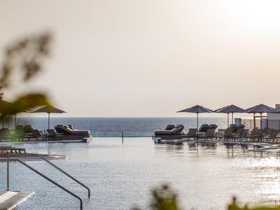 Zwembad met ligstoelen en parasols bij de zee tijdens zonsondergang