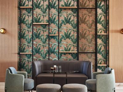 Gezellig zithoekje met bank, fauteuils en decoratieve muur in een hotel.