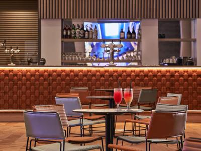 Moderne hotelbar met bruine lederen stoelen, zwarte tafel en rode drankjes.