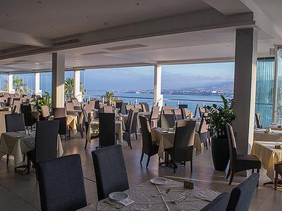 Elegant restaurant met zeezicht en gedekte tafels in een lichte ambiance.