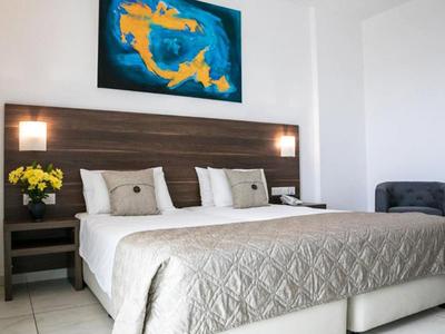 Helles Schlafzimmer mit Doppelbett, grauem Steppbett, Nachttischen, gelben Blumen und blauem Koi-Gemälde.