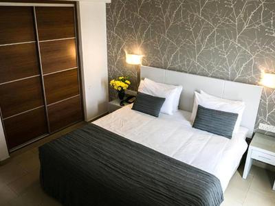 Modernes Schlafzimmer mit großem Doppelbett, grauen Akzenten, Nachttischen und Holzschrank.