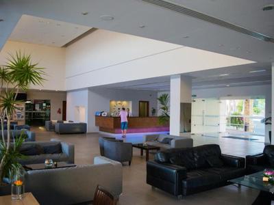 Großer moderner Aufenthaltsraum mit Ledersofas, Billardtisch und hohen Pflanzen.