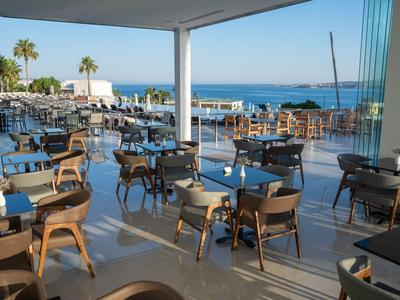 Offener Außenbereich eines Restaurants mit Blick auf das Meer und Palmengärten.