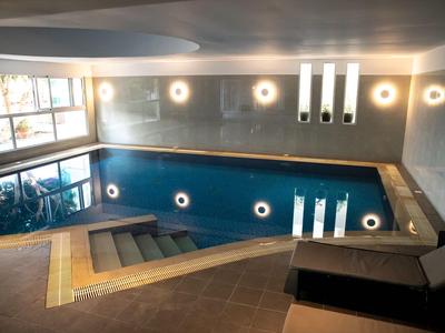 Innenpool mit Treppen, beleuchteten Wänden und Lounge-Bereich.