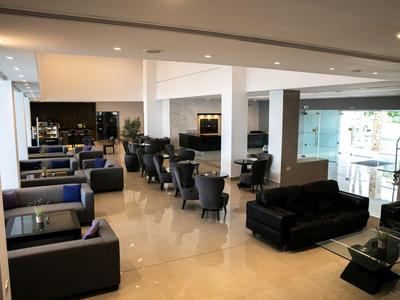 Moderner Hotel-Loungebereich mit schwarzen Sesseln, Tischen und heller Marmorbodenoptik.