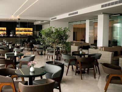 Moderner Hotel-Loungebereich mit Tischen, Stühlen und gemütlicher Atmosphäre.