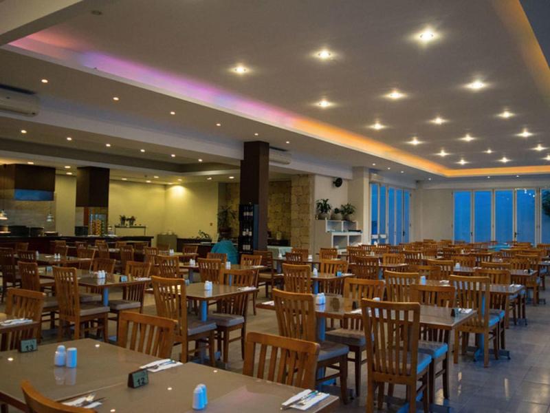 Großer, moderner Speisesaal mit Holzstühlen, gedeckten Tischen und gedämpfter Beleuchtung.