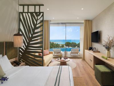 Habitación de hotel moderna con cama doble, tabique y vista al mar a través de grandes ventanas.