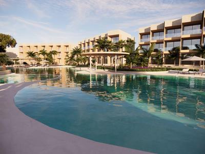 Gran piscina del hotel con tumbonas y edificios modernos al atardecer.