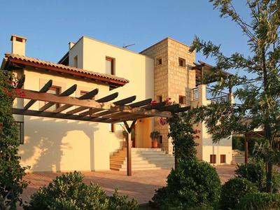 Gelbes Haus mit Holzbalken, Treppe, Garten und Bäumen bei Sonnenuntergang.