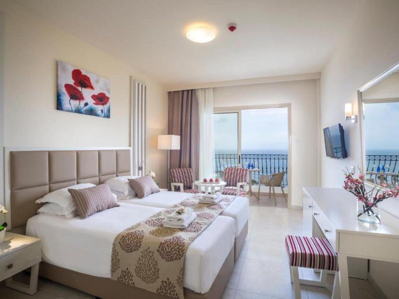 Modern eingerichtetes Hotelzimmer mit zwei Betten, Balkon und hellen Farben.