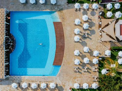 Überblick über einen Pool mit blauen Fliesen neben Liegestühlen und Sonnenschirmen.