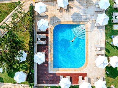 Vogelperspektive eines rechteckigen Hotelschwimmbeckens mit Sonnenschirmen und Liegestühlen.