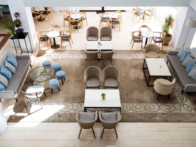 Moderner Hotel-Loungebereich mit verschiedenen Sitzgruppen und Tageslicht von oben.