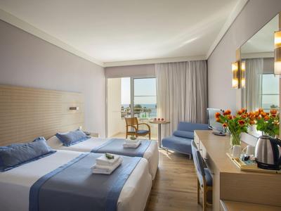 Modernes Hotelzimmer mit zwei Betten, Balkon und Blick aufs Meer.