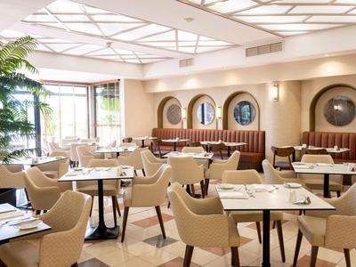 Elegantes Hotelrestaurant mit bequemen Stühlen, runden Tischen und natürlichem Licht.