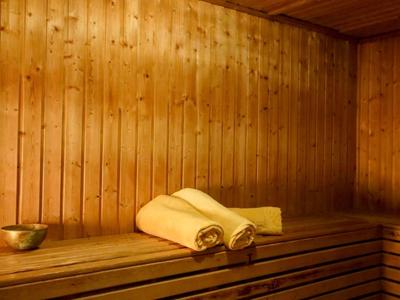 Gemütliche Sauna aus hellem Holz mit zwei aufgerollten Handtüchern auf der Bank.