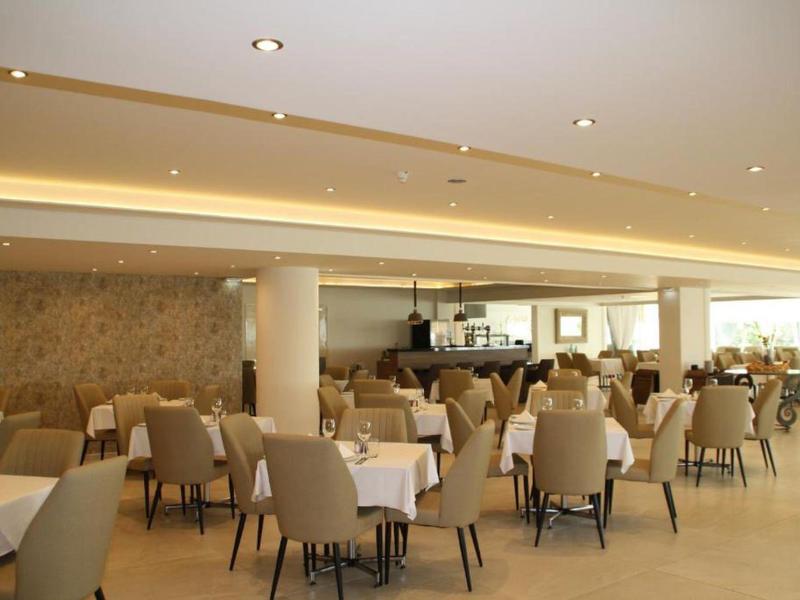 Großer heller Speisesaal mit vielen gedeckten Tischen und beigen Stühlen in modernem Stil.