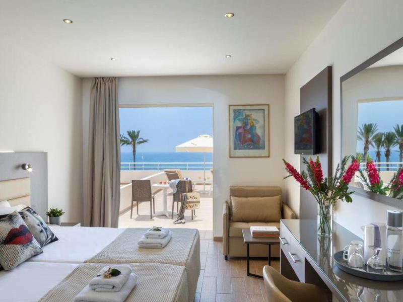 Helles Doppelzimmer mit Blick auf das Meer, Balkon, Sitzbereich und moderner Einrichtung.