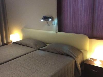 Tweepersoonskamer met twee eenpersoonsbedden, nachtlampen en gesloten gordijnen.