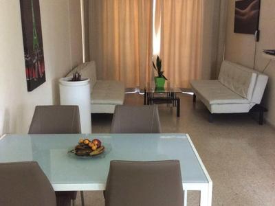 Moderne woon- en eetkamer met wit meubilair en gordijnen in warm licht.