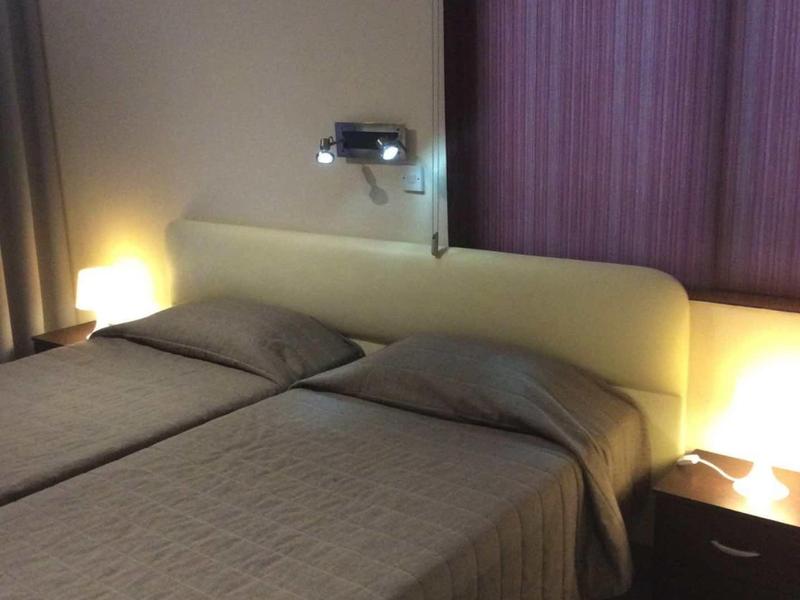 Pokój hotelowy z dwoma pojedynczymi łóżkami, lampkami nocnymi i zasłoniętymi zasłonami.