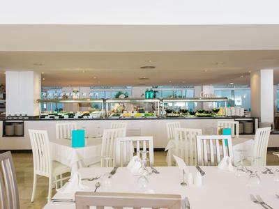 Helles, modernes Restaurant mit weiß gedeckten Tischen und Holzstühlen.