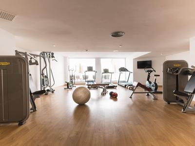 Heller Fitnessraum mit Holzfußboden und verschiedenen Trainingsgeräten inklusive Gymnastikball.