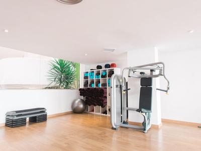 Moderner Fitnessraum mit Kraftstation, Gewichten und Aerobic-Stufen auf Holzboden