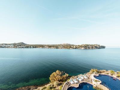 Vue sur une côte calme avec de l'eau claire et une piscine au premier plan.