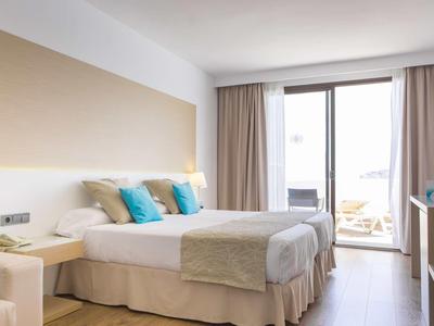 Chambre d'hôtel moderne avec lit double, balcon et rideaux clairs.